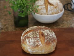 a loaf of bread sitting on top of a wooden cutting board next to a potted plant