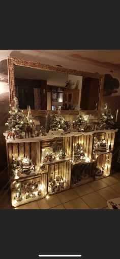 a christmas display with lights and trees on the top shelf in front of a mirror