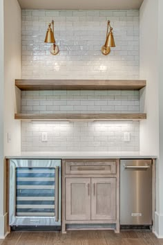 an empty kitchen with stainless steel appliances and white subway backsplash, built - in shelving