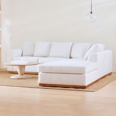 a white couch sitting on top of a hard wood floor next to a coffee table