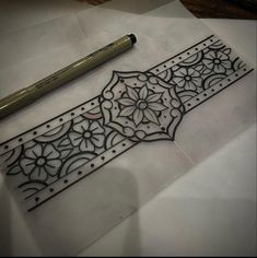 an intricately designed piece of paper next to a pencil on top of some white paper