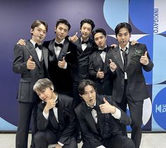 a group of young men in tuxedos posing for a photo with their thumbs up