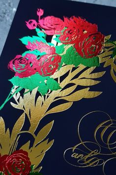 a close up of a card with flowers on the front and gold foiled lettering