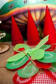 a table topped with red and green plates covered in paper hats on top of a wooden table