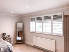 a bed room with a neatly made bed next to a window and a radiator