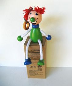 a toy sitting on top of a cardboard box with a red hair and green nose