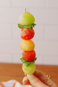 a person holding up a fruit skewer made out of candy apples and watermelon