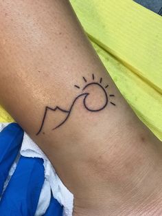 a woman's arm with a tattoo on it that has the sun and mountains