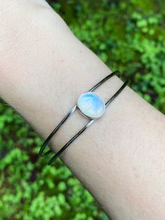 This classic bracelet is set in the center with a rainbow moonstone cabochon, with an elegant & sleek split style cuff. Adjustable to fit most wrists by gently opening and closing around the wrist. Sterling silver. Stone is approx. 1/2" long. Adjustable Oval Modern Cuff Bracelet, Elegant Silver Bracelets With Moon Phase, Elegant Silver Moon Phase Bracelet, Modern Silver Bangle With Gemstone, Modern Silver Gemstone Bangle, Modern Adjustable Cabochon Jewelry, Modern Adjustable Oval Bangle, Elegant Moonstone Cuff Bangle Bracelet, Elegant Moonstone Bangle Cuff Bracelet