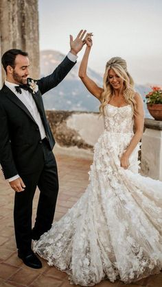 a man and woman in formal wear standing next to each other on a stone walkway