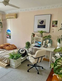 a bed room with a neatly made bed next to a desk and plant pots on the floor