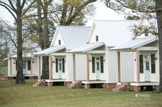 several small white houses in the grass near trees