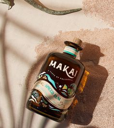 a bottle of makai rum sitting on the ground next to a lizard's tail