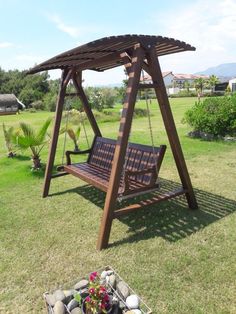 a wooden swing set sitting on top of a grass covered field next to a potted plant