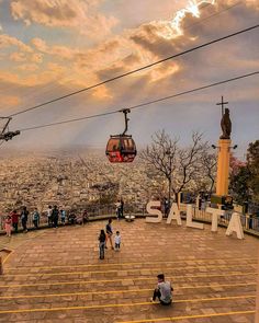 two people sitting on the ground in front of a cable car over a cityscape