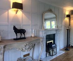 a living room with a fireplace, mirror and statue on the mantle in front of it