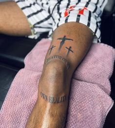 a man with a cross tattoo on his leg sitting in front of a pink towel