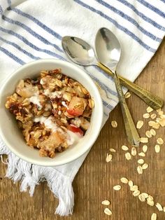 a bowl filled with oatmeal sitting on top of a table next to spoons