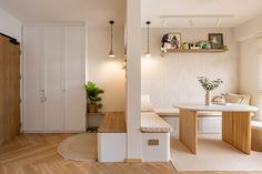 a room with wooden floors, white walls and a bench in the corner next to a window