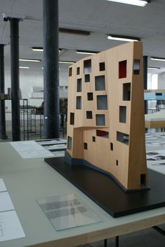 a wooden sculpture sitting on top of a table in an office building with lots of windows