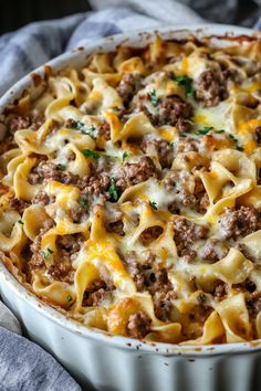 a casserole dish with meat and cheese in it on a blue towel next to a fork