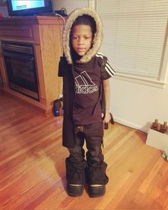 a young boy standing in front of a tv wearing skis and a hoodie