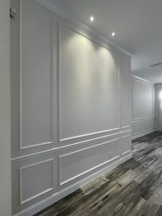 an empty room with wood flooring and white paneled walls on either side of the wall