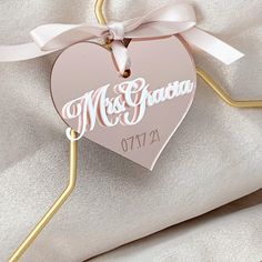 a pink heart shaped ornament hanging from a gold ribbon