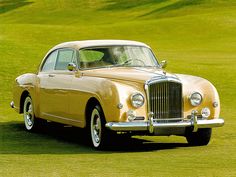 an old fashion car is parked on the grass in front of a green golf course