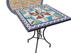 a mosaic table with an iron base and chair cushion on the top, sitting on a white background