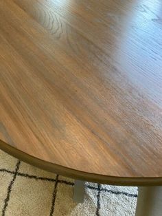 a close up of a wooden table top on a carpeted floor with white rugs