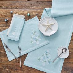 napkins with starfish design and silverware on wooden table top next to utensils