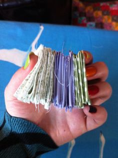 a person holding several pieces of fabric in their hand with nails on top of them