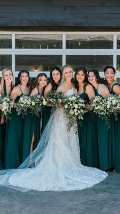 a group of bridesmaids pose in front of a building with their bouquets