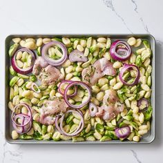 a tray filled with meat and vegetables on top of a table next to a marble counter