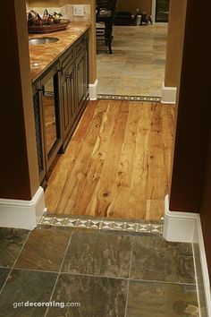 an open door leading into a kitchen with wood floors and tile flooring on the walls