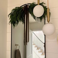 a mirror hanging from the side of a wall next to a christmas wreath and other decorations