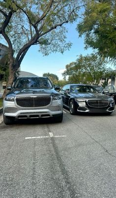 two cars parked next to each other on the side of a road with trees in the background