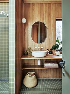 a bathroom with wood paneling and green tiled walls, along with a round mirror on the wall