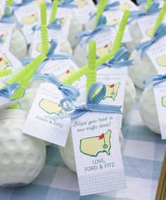 golf balls with tags tied to them sitting on a blue and white checkered table cloth