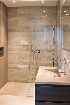 a bathroom with a walk in shower next to a sink and mirror on the wall