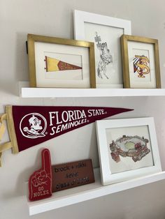 three framed pictures are hanging on the wall next to two baseball bats and a pennant