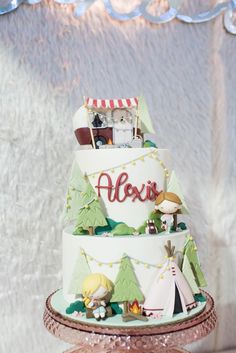 a three tiered cake is decorated with campers and tents