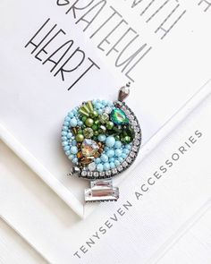 a close up of a brooch with beads and charms on top of a book