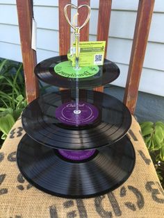 three black records stacked on top of each other in front of a wooden chair outside