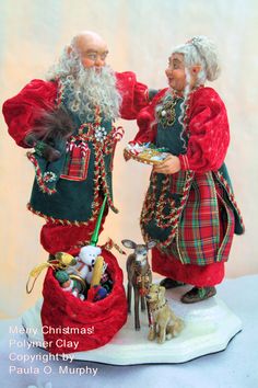 two figurines are standing next to each other with christmas decorations in their hands