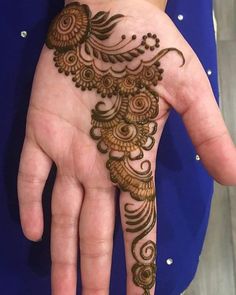 a woman's hand with henna tattoos on it, showing the intricate design