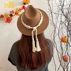 a woman wearing a brown hat with white tassels on her head and long hair