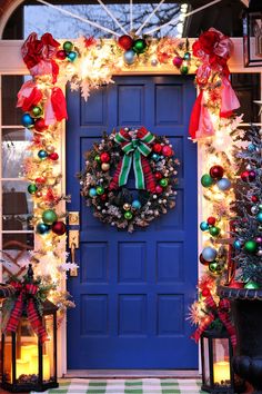 a blue front door decorated for christmas with wreath and lights on it's sides