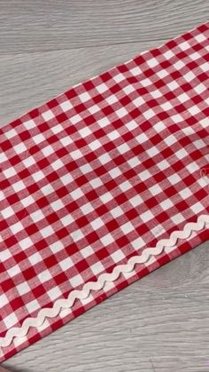 a red and white checkered table cloth with scalloped edges on a wooden surface